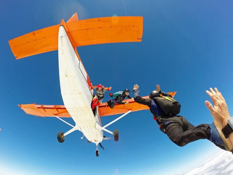 一群跳伞的朋友从橙色的飞机上跳下来