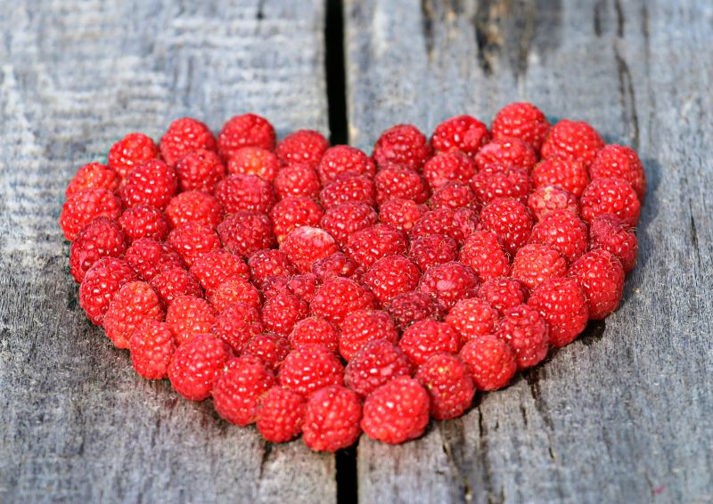 木板上红色树莓摆成的爱心形状
