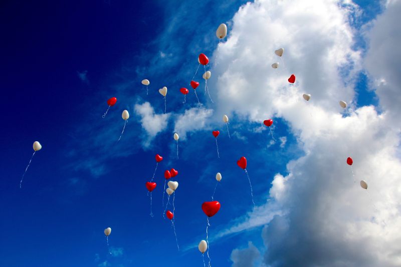 蓝色天空中漂浮这红色和白色的爱心气球
