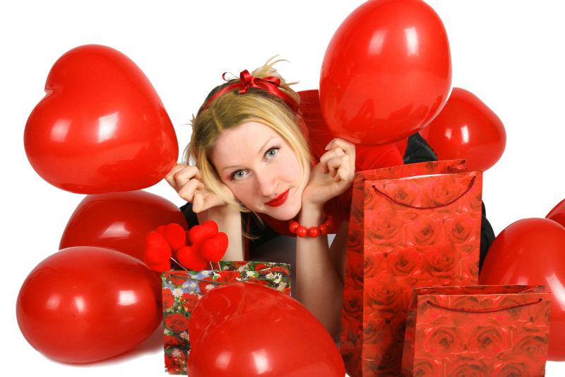 美女在一堆红色气球和礼物盒子间