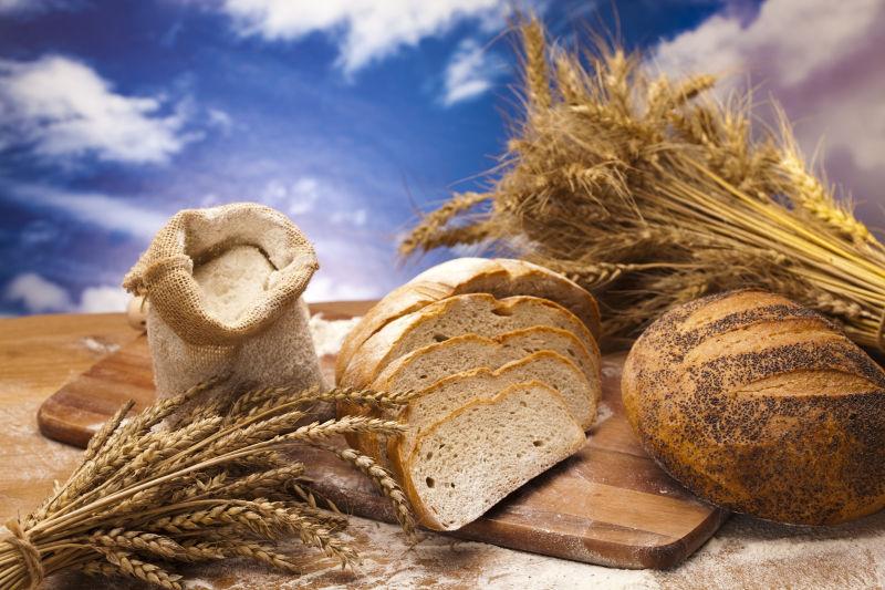 户外木桌上的麦穗和美味的小麦面包