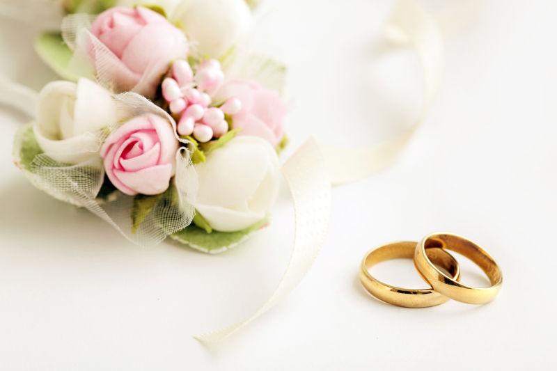 白色背景下的结婚戒指和鲜花