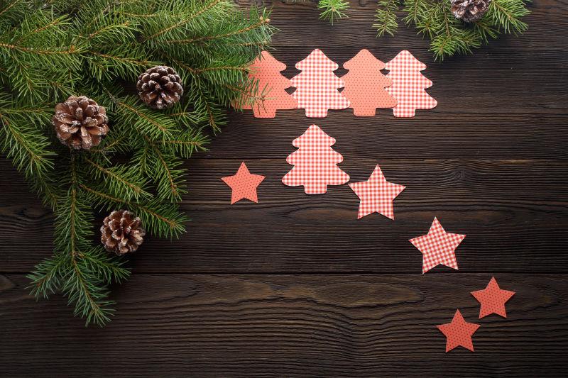 装饰着圣诞树枝的木板上放着星星和圣诞树形状的卡片