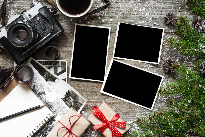 褐色木纹理桌上的圣诞树枝黑色老式照相机和空白相片