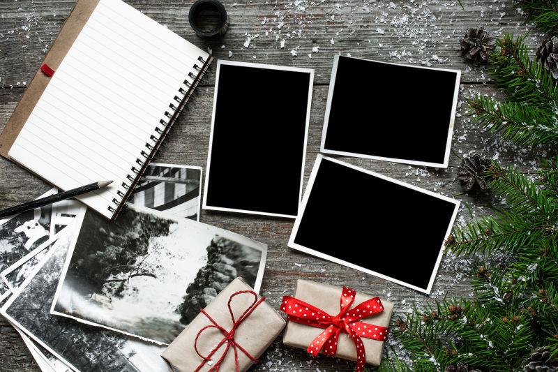 木桌上的圣诞树枝礼物盒黑色老式照相机和空白相片