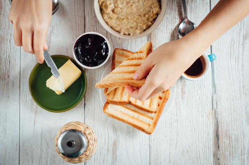 木桌上加黄油和果酱的自制烤面包和咖啡