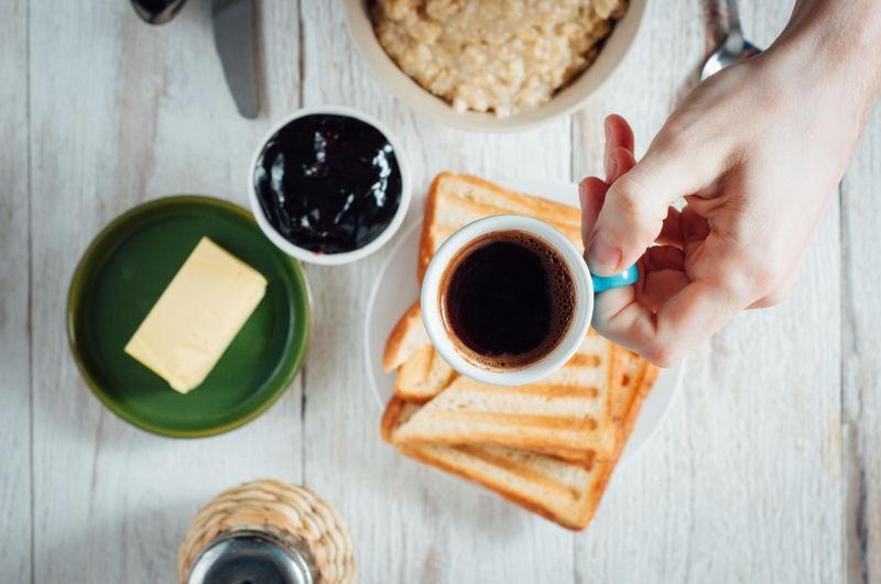 木桌上的黑咖啡和自制的果酱和黄油面包