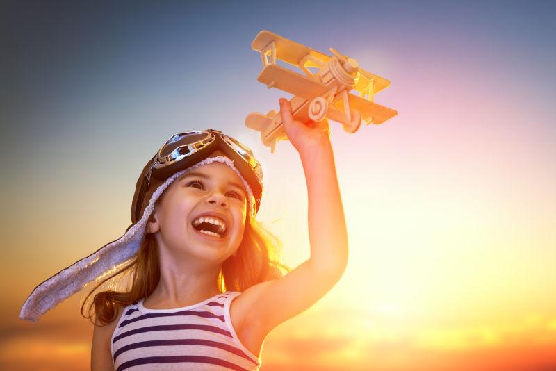 在日落时对着天空玩玩具飞机的孩子