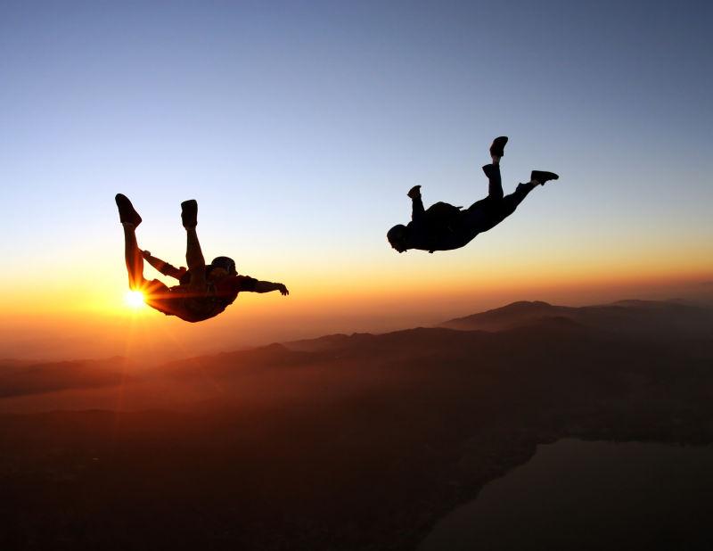 夕阳下的天空有两个跳伞员