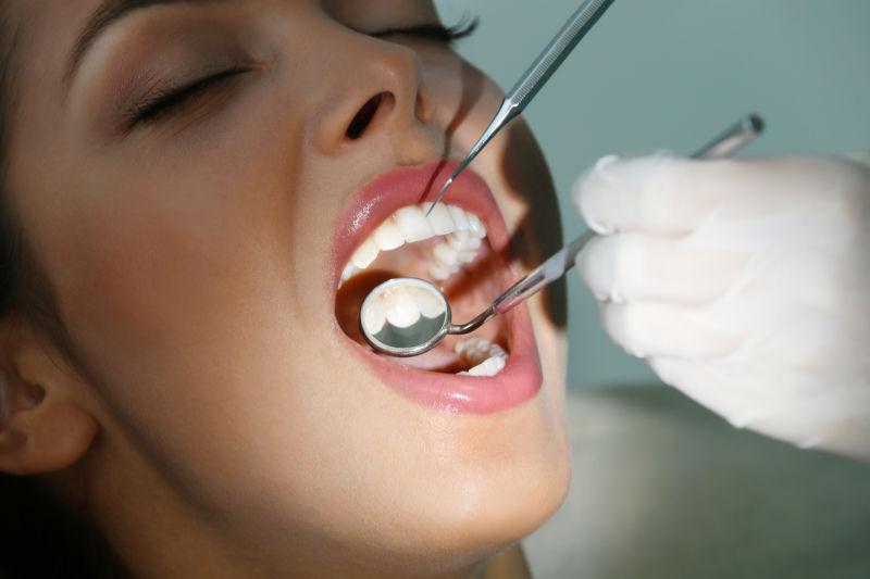 戴白手套用仪器检查美女牙齿的牙医