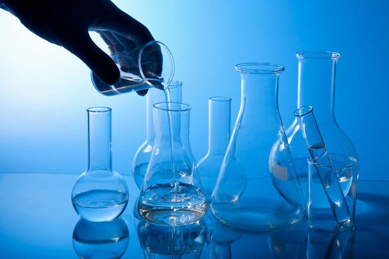 蓝色背景下实验室里向玻璃瓶里倾倒液体