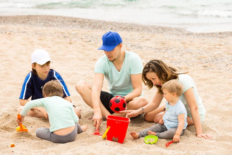 父母和孩子在海边玩沙子