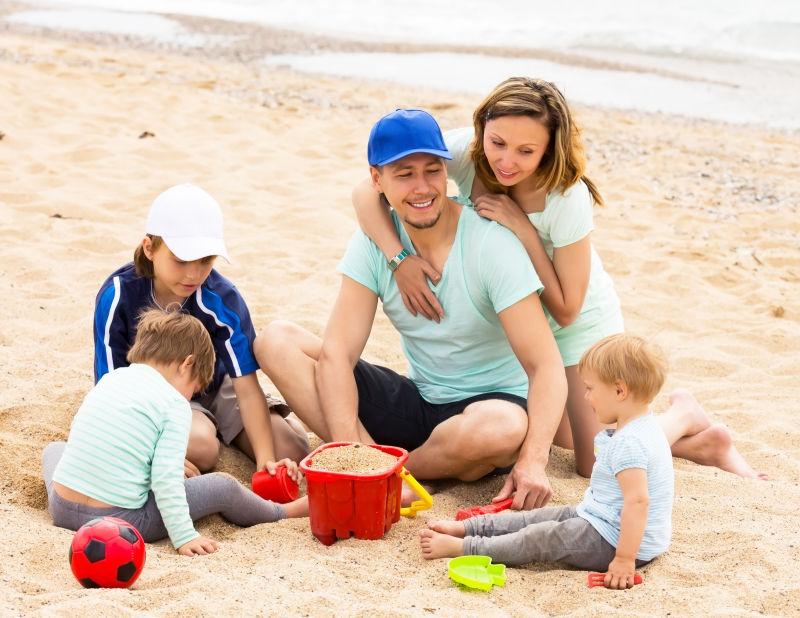 微笑的父母带着孩子们在沙滩上休息