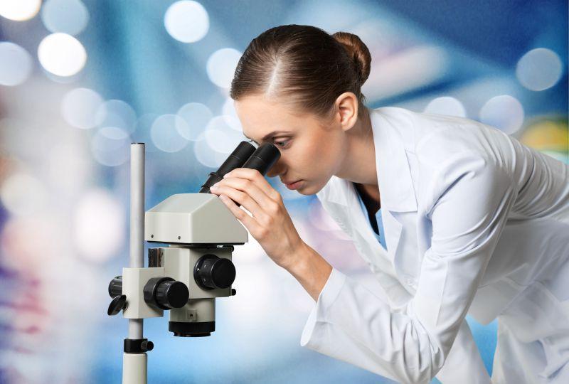 使用显微镜研究的穿着白色衣服的女性研究人员