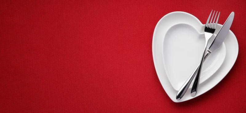 红色桌布上白色盘上的刀叉