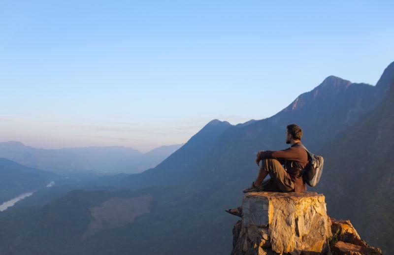 坐在山顶山看风景旅游的男人