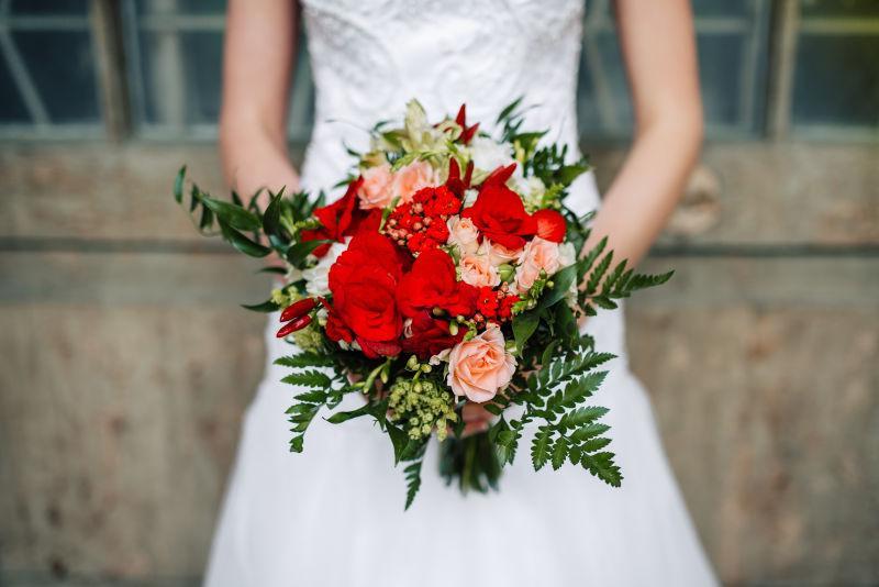 穿着婚纱的新娘手中的红色婚礼花束