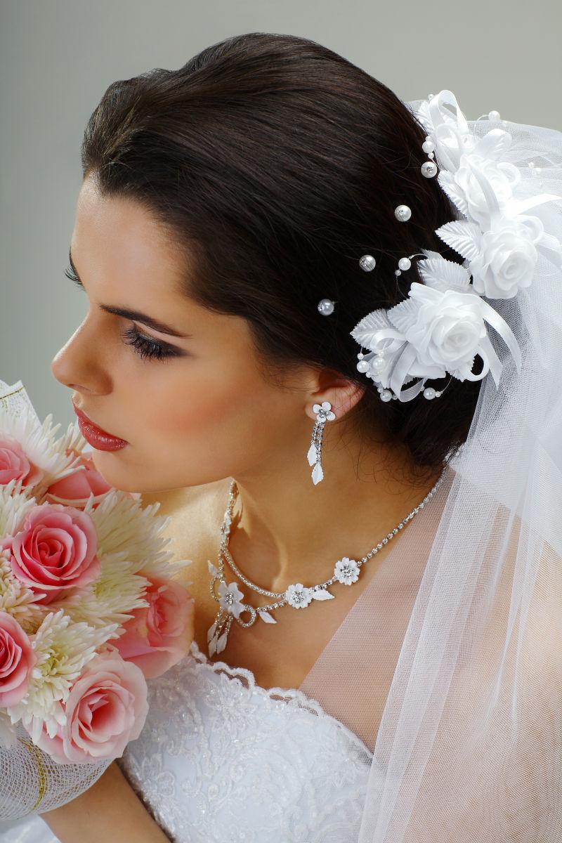 穿着白色婚纱的新娘捧着一束玫瑰花