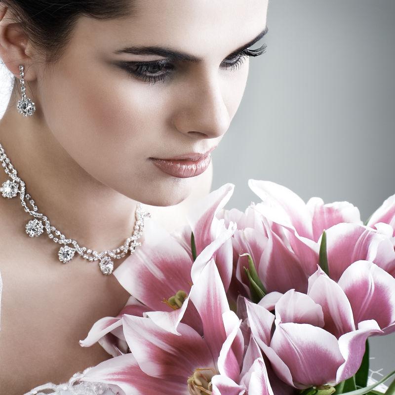 捧着鲜花的新娘带着美丽的钻石耳环和项链