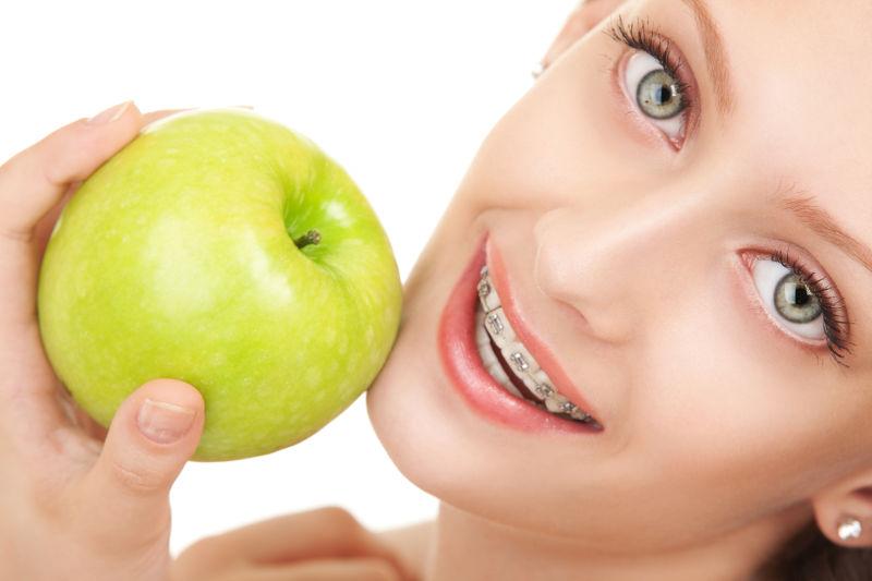 戴牙套的美女拿着一个苹果