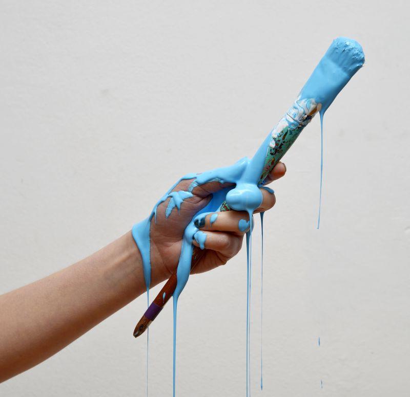 沾满蓝色颜料的画笔和手