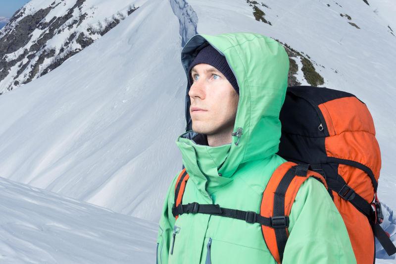 冬季背景下带背包的登山者望着山顶