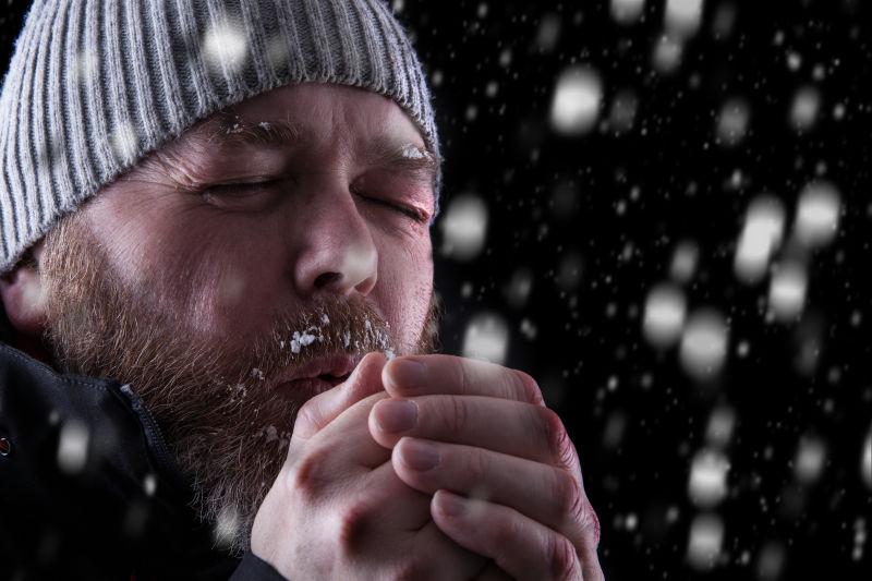 冰冷的人站在暴风雪中试图保暖