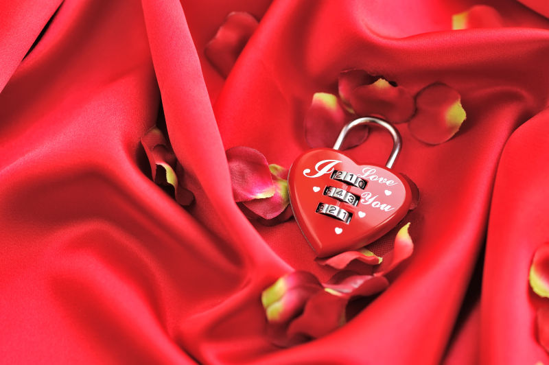 红色绸缎上的玫瑰花瓣和情人锁