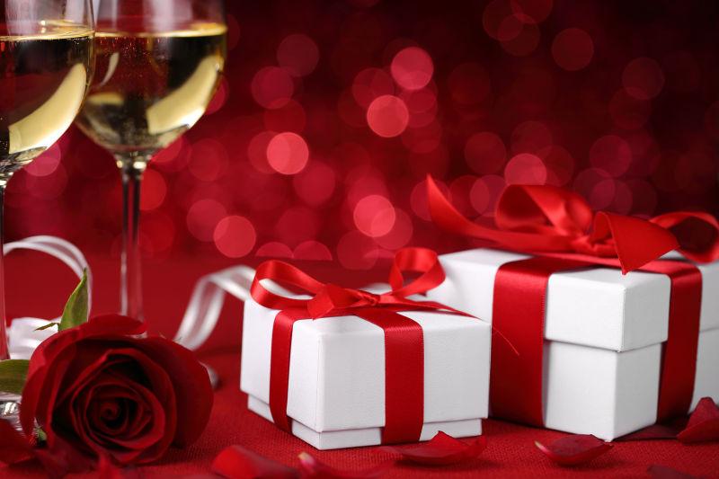 香槟酒杯边的玫瑰花和情人节礼物盒