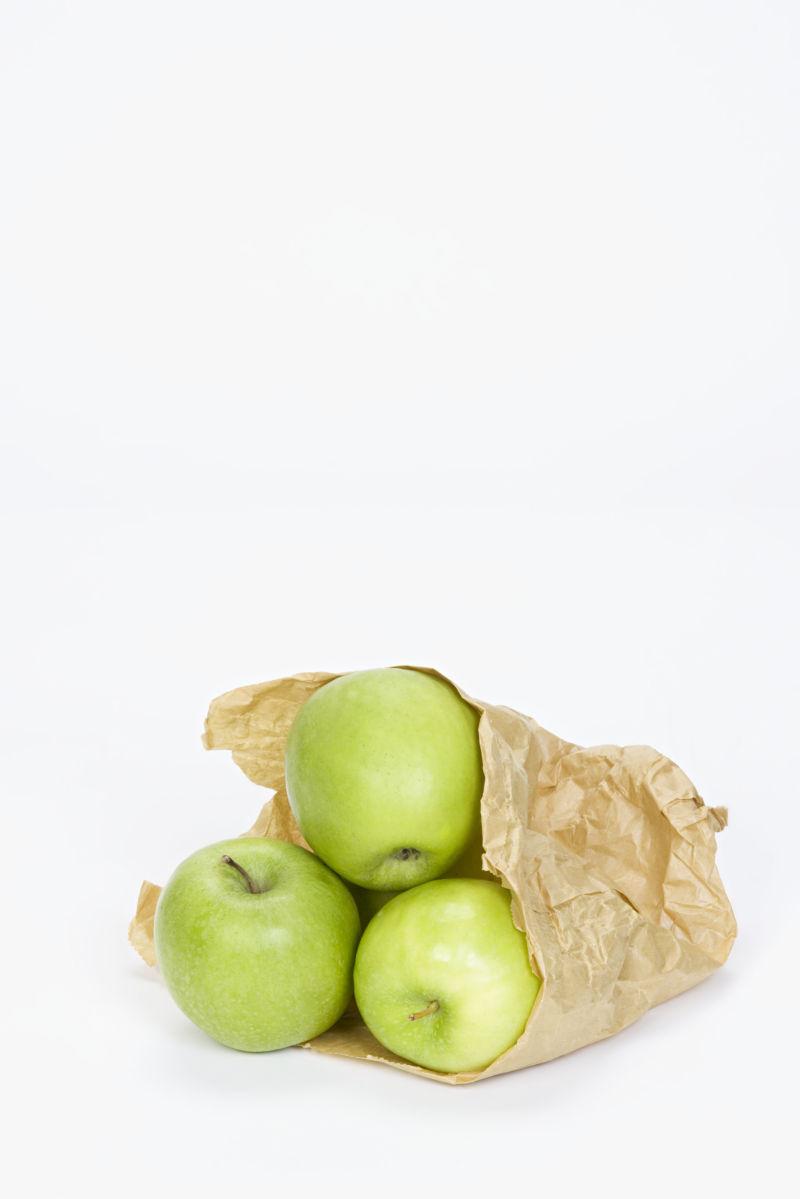 白色背景上购物袋里的绿色苹果