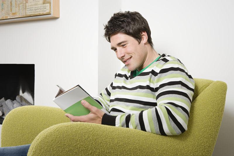 坐在沙发上的男人在看着书籍