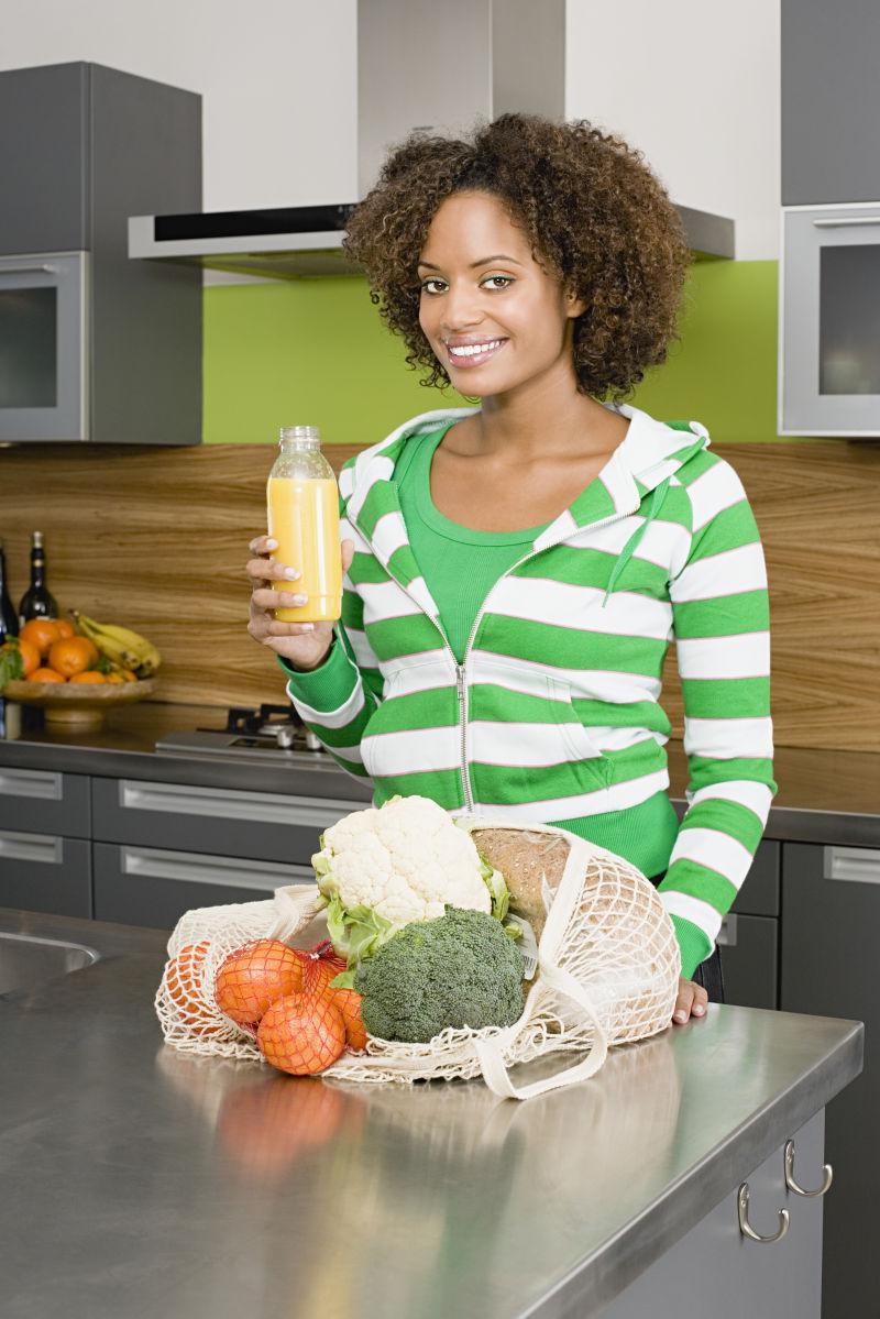 穿着绿色条纹衣服的黑人妇女前面放着蔬菜食材