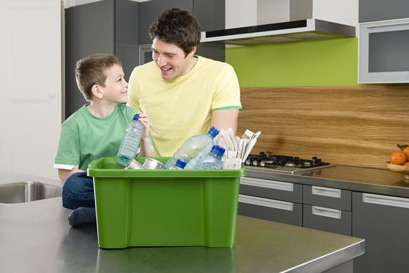 爸爸和儿子在整理桌面装着可回收垃圾的绿色箱子