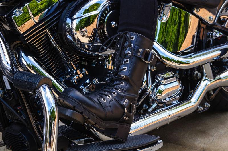 金属色的摩托车和骑士的皮靴