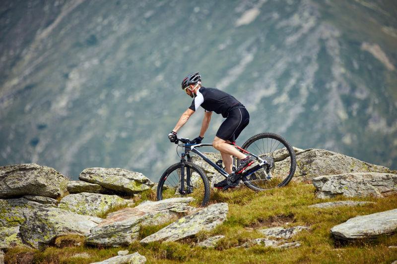 穿着运动装备和头盔骑在崎岖的小径上的山地自行车骑手