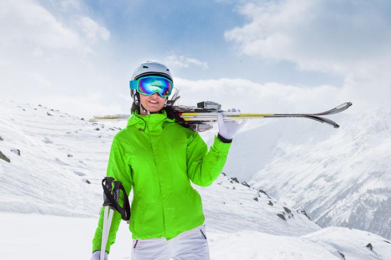 滑雪场穿着绿色衣服的滑雪美女拿着滑雪工具