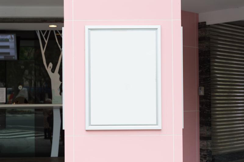 建筑背景下的粉色墙上的空白广告牌