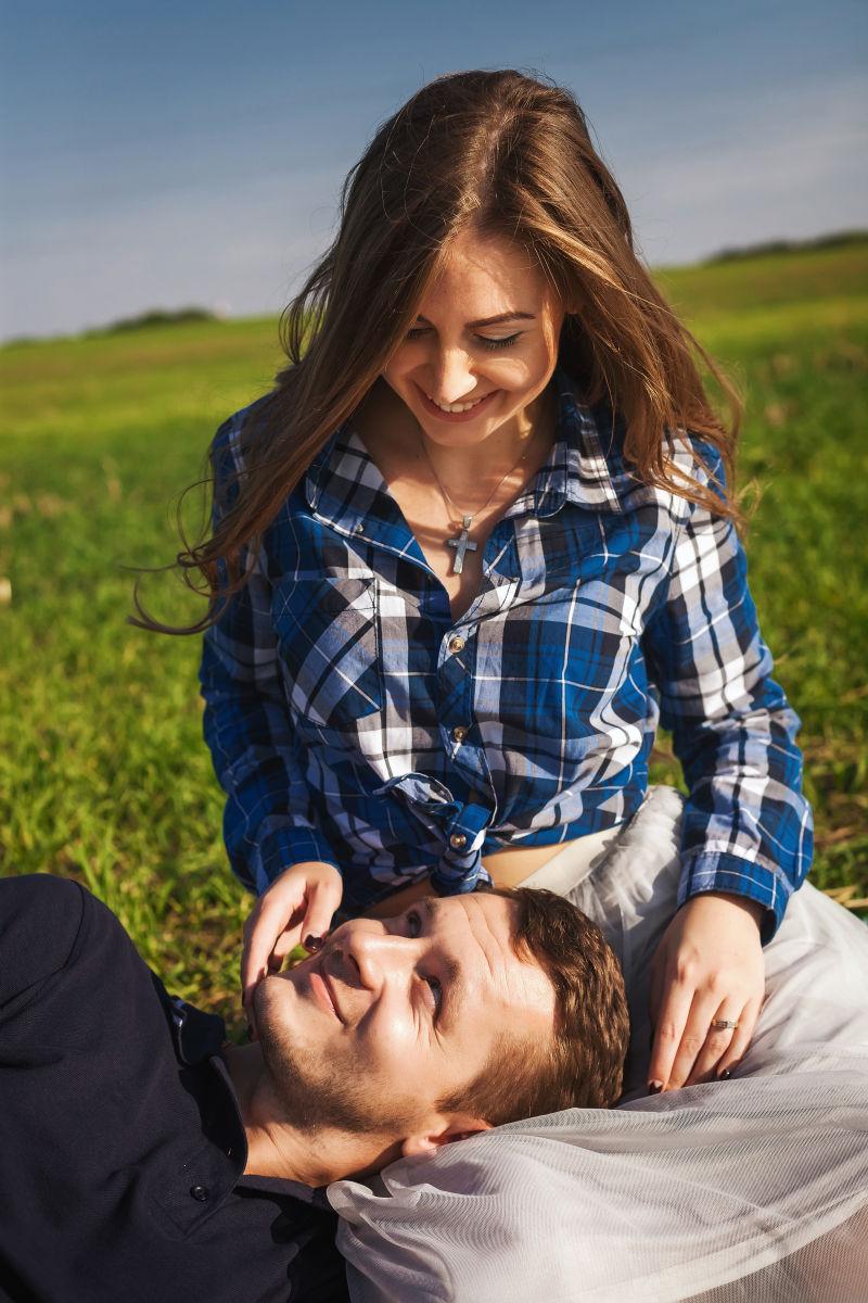 户外草地上躺在女朋友腿上的男人