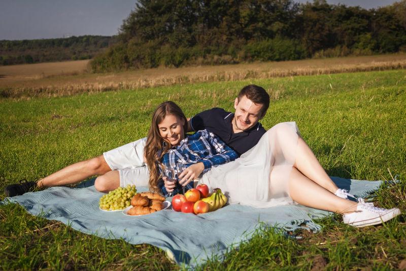 户外草地上野餐的年轻夫妇