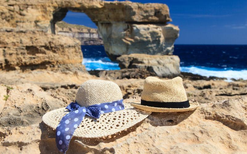 海滩边岩石上的两个遮阳帽