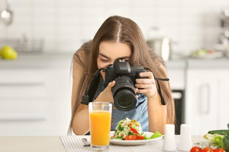 白色厨房背景中用单反拍摄美食的女摄影师