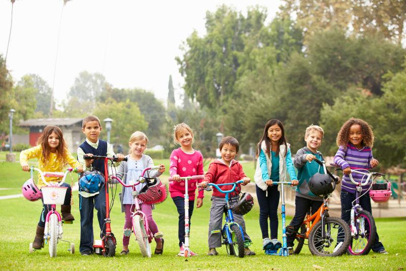 公园里骑自行车和踏板车的小孩