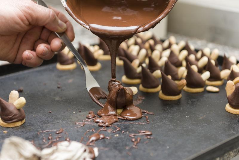 糕点厨师用融化巧克力覆盖饼干