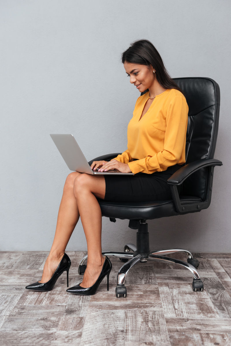 成功的女人坐在椅子上玩笔记本电脑上