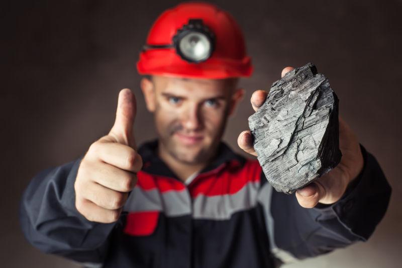 拿着煤炭的工人正在竖大拇指