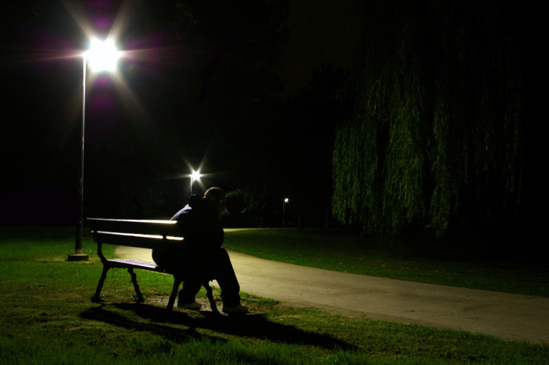 夜晚路灯照耀下的公园椅子上坐在一个孤独的人
