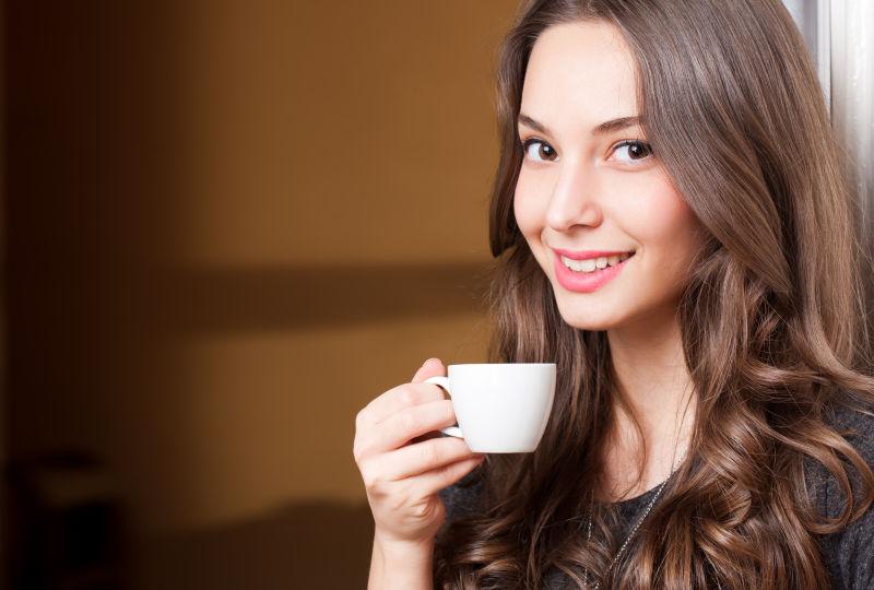 一个年轻漂亮的黑发女子拿着杯咖啡