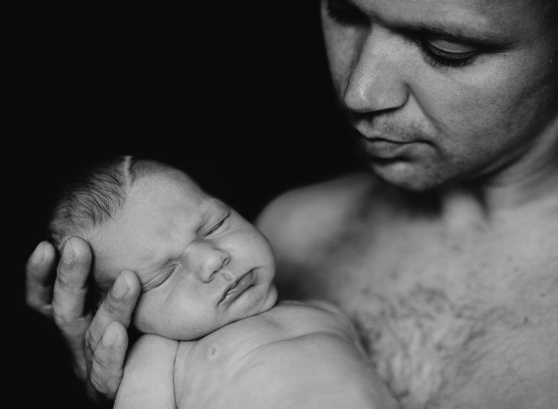 黑色背景中抱着新生儿的父亲