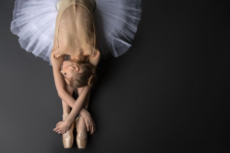 优雅的芭蕾舞演员坐在地板上