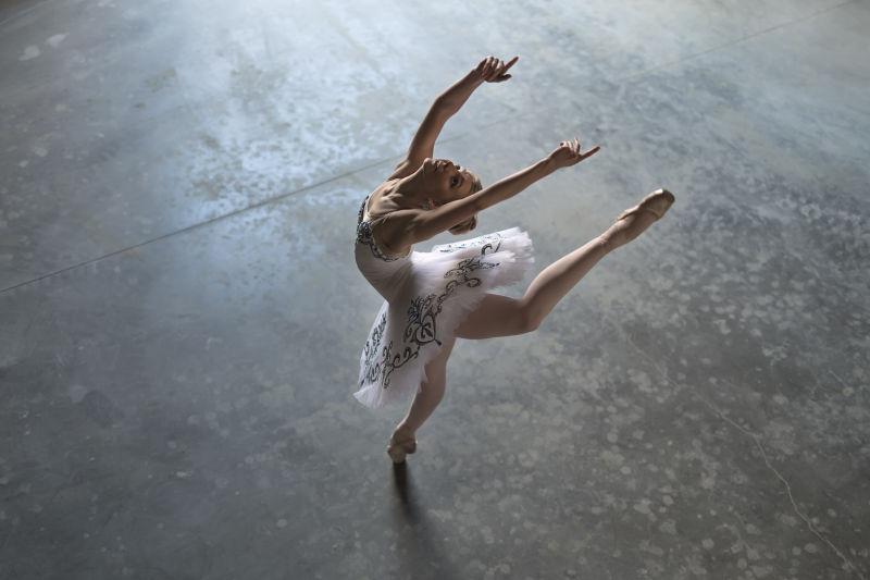 一个漂亮的芭蕾舞演员穿着白色的兔兔在大厅里摆姿势